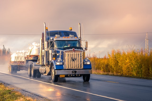 truck driving down a wet road at sunrise after a rain storm