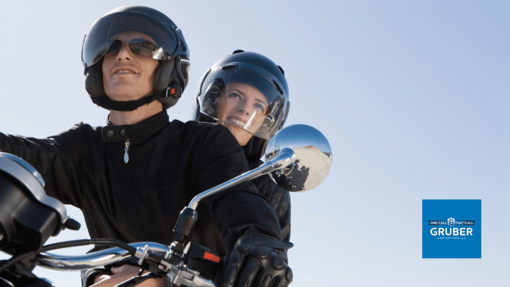man and woman on motorcycle wearing healmets - Gruber Law