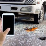 A person takes a snapshot of the front of a truck at an accident scene with a cell phone. You should get medical help and then talk with a personal injury lawyer about recovering your damages after a crash with an Amazon truck.