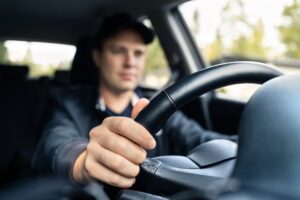 A rideshare driver guides a vehicle. Rideshare companies do cover damages in accidents, but coverage depends on who was at fault and what stage the driver was in at the time of the crash.