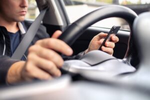 A rideshare driver uses a cell phone while at the steering wheel. If you get hurt in a Lyft accident, you may be able to recover damages. A car accident attorney can determine liability and deal with the insurance company for you.