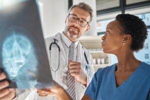 Doctors are looking at an X-ray of a brain injury. The patient with this severe head trauma might get a higher-than-average settlement for brain injury.
