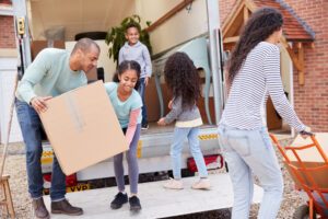 Children help their parents unload a moving truck.